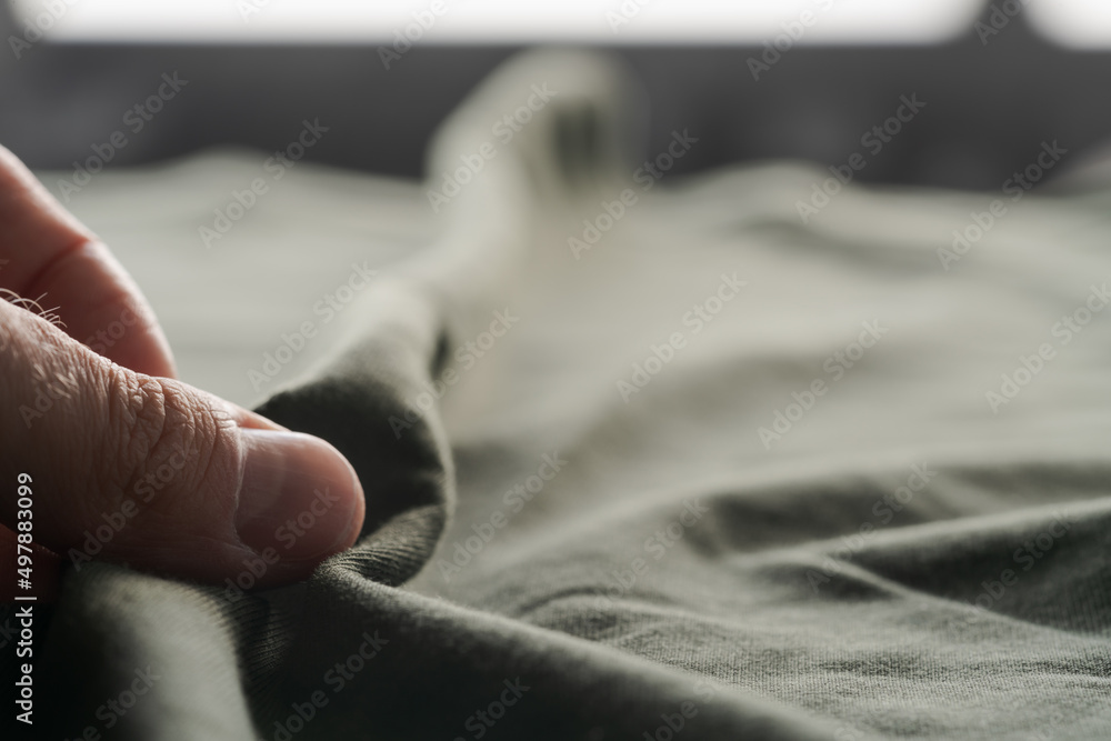 Fototapeta premium man hand touching green cotton fabric