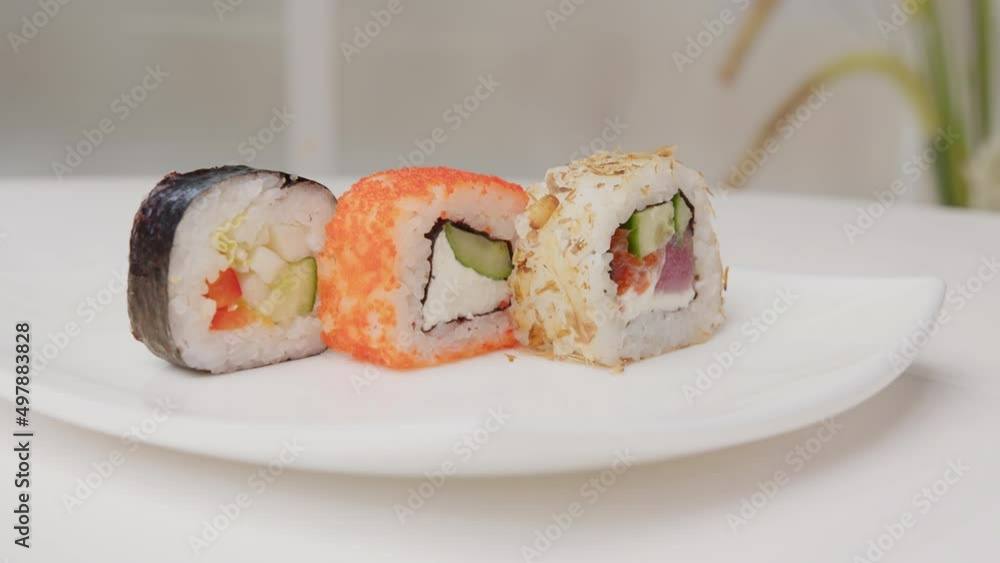 Set of assorted sushi rolls rotating on serving plate on white table close up. Sushi menu, Japanese food. Set of assorted sushi rolls rotating on serving plate on white table close up. Sushi menu, Japanese food.