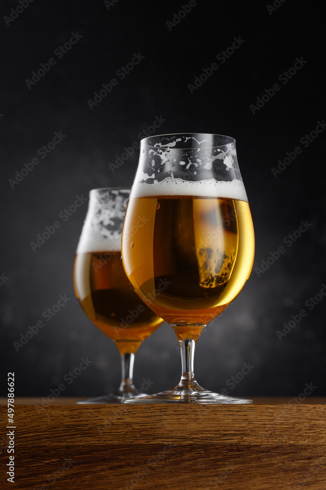 Two glasses of light beer on dark background. Selective focus Two glasses of light beer on dark background. Selective focus