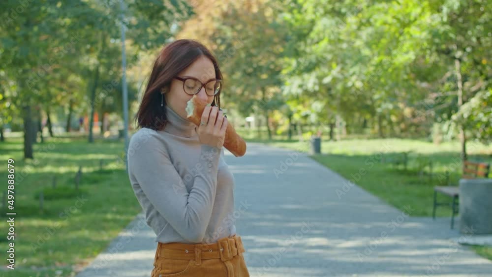 young happy woman eating baguette in city park. girls have fun together. youth, serenity, summer or autumn park. young happy woman eating baguette in city park. girls have fun together. youth, serenity, summer or autumn park.