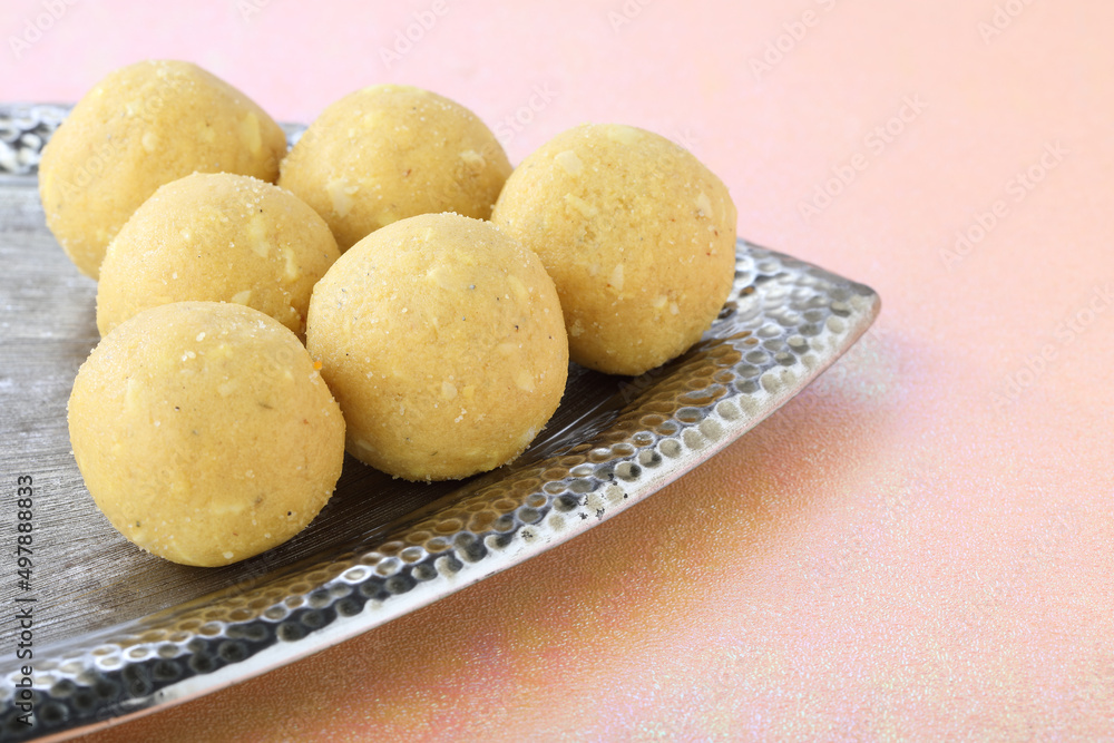 Indian festival diwali sweet motichur laddu serve in a decorative silver plate with colourful lamps Indian festival diwali sweet motichur laddu serve in a decorative silver plate with colourful lamps