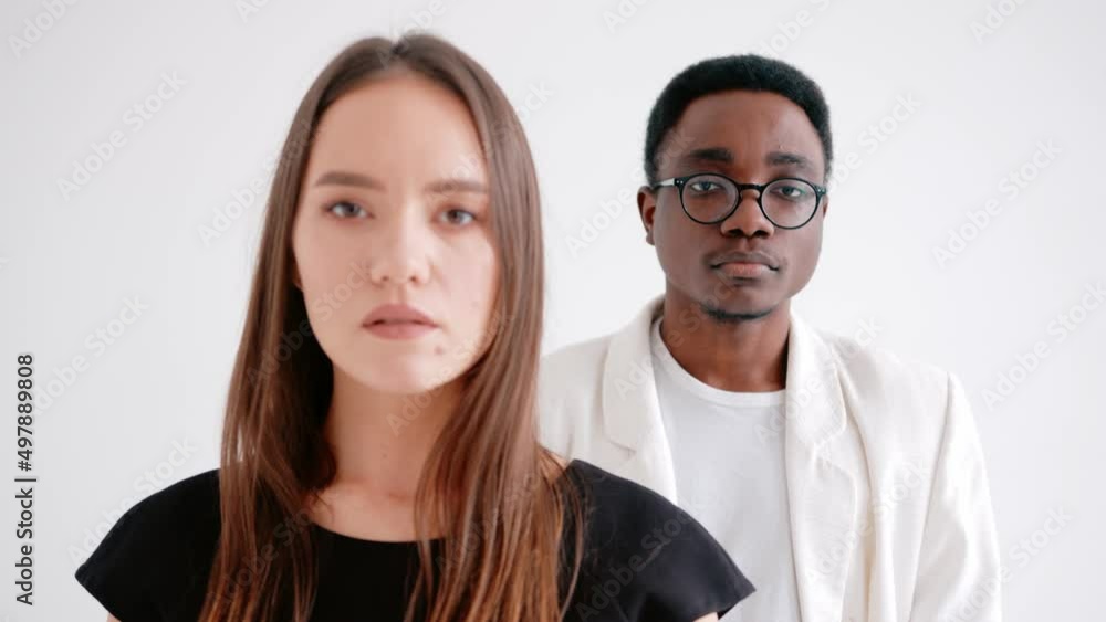 A caucasian young girl and african american guy look in different directions and then turn to the camera. Concept of human relations