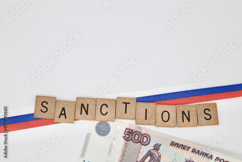 Russian ruble banknote on white background with ribbon of Russian Flag . Sanction word with Russian banknote and flag. Russian ruble under sanctions.