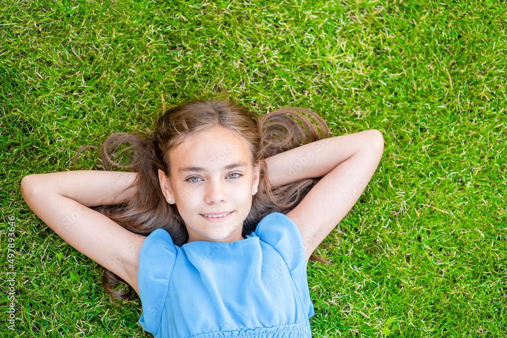 Happy teen girl lying on a grass, top down view Happy teen girl lying on a grass, top down view