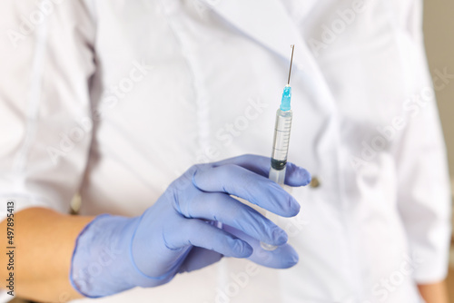 Nurses hand in a rubber glove holds a syringe with medicine