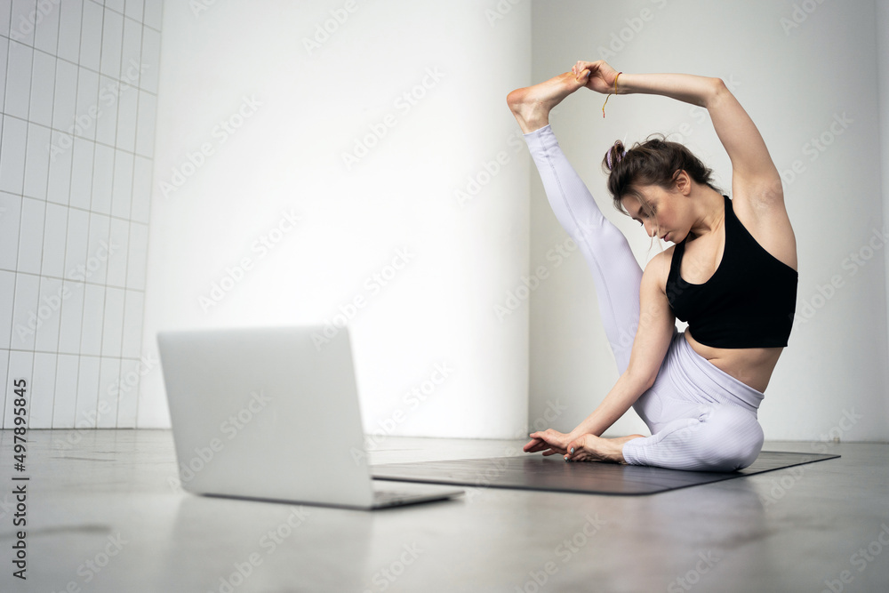 Online laptop video workout woman sports exercises gymnastics in a fitness club, yoga asana pose Online laptop video workout woman sports exercises gymnastics in a fitness club, yoga asana pose