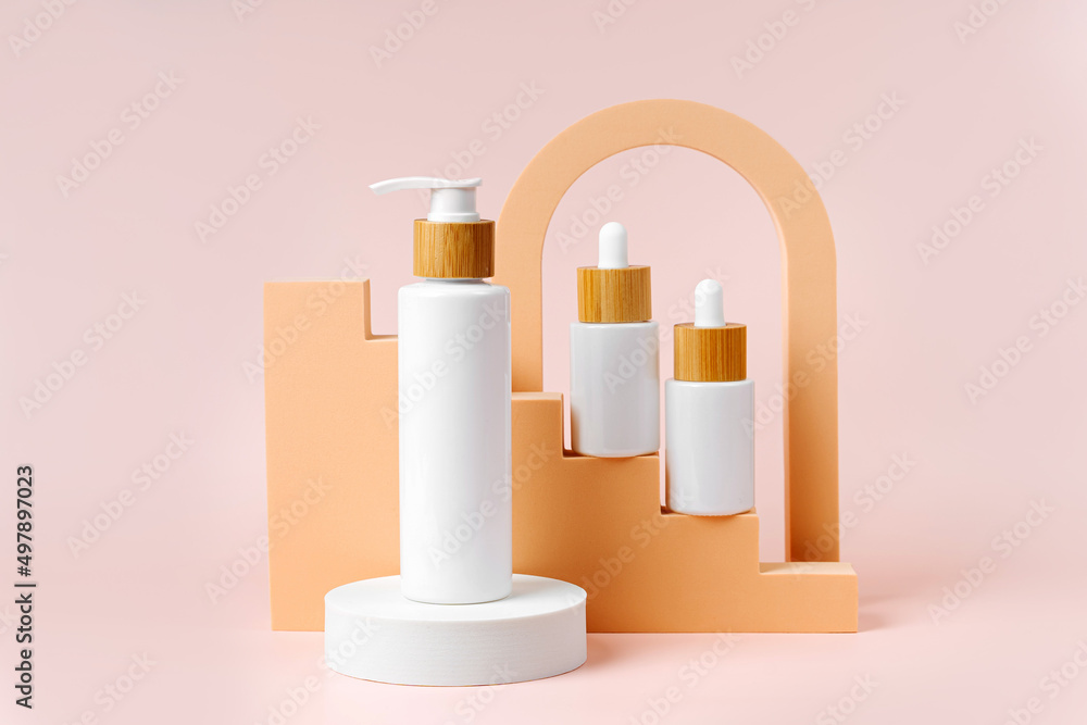 Pump bottle with white dropper bottles on beige stairs with geometric shapes and podium. Background for branding and packaging presentation. Natural skincare beauty product concept. Pump bottle with white dropper bottles on beige stairs with geometric shapes and podium. Background for branding and packaging presentation. Natural skincare beauty product concept.