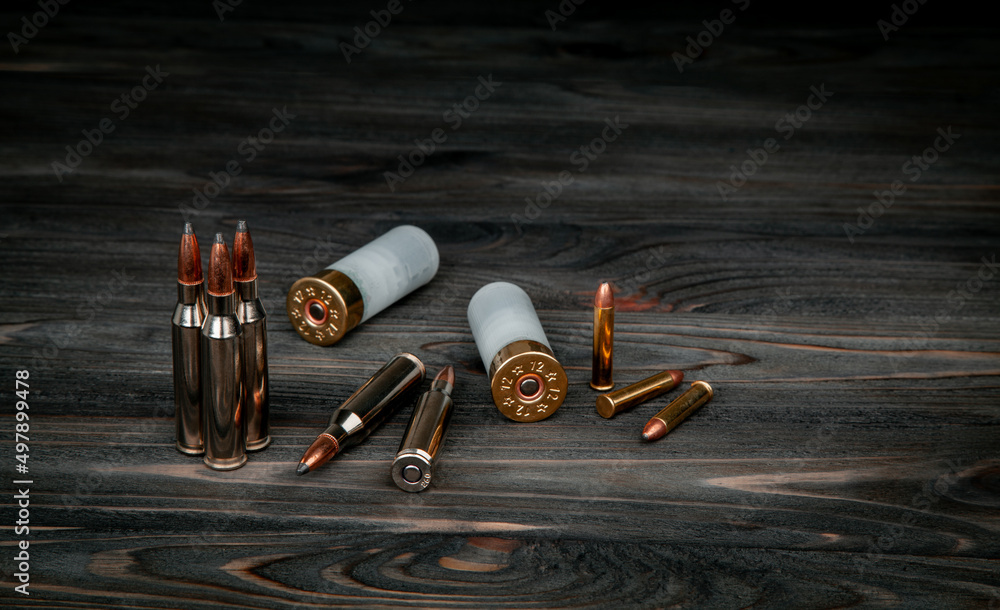 Various types of ammunition on a wooden surface. Cartridges for weapons. Dark back. - obrazy, fototapety, plakaty 