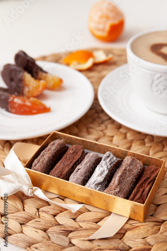 Sweet truffle dessert in cocoa powder with a cup of coffee and marmalade slices of orange in chocolate on the back background.