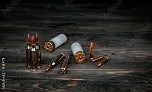 Various types of ammunition on a wooden surface. Cartridges for weapons. Dark back. photo