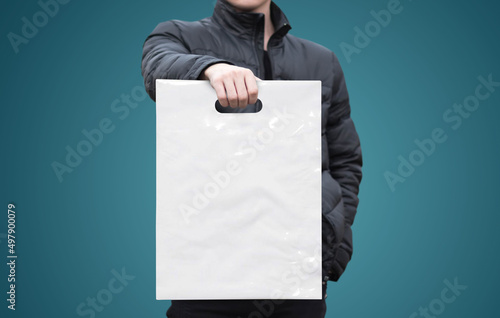 A man holds a mockup white plastic bag. A man with a package on isolated background