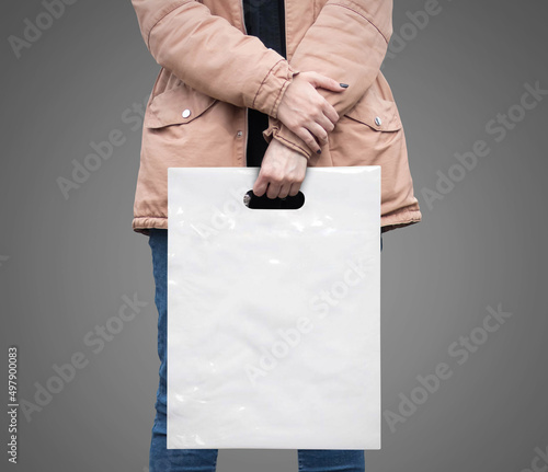 The girl is holding a mockup white plastic bag. A girl with a package on isolated background