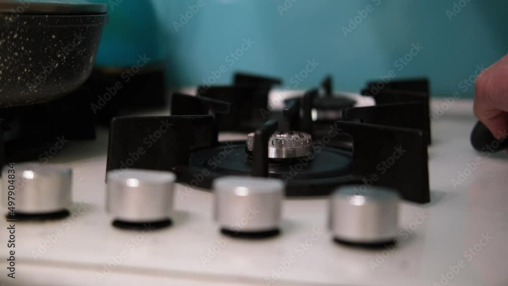 The hand turns on the gas burner on the kitchen stove. Gas does not burn well on a small comfort on the stove. The concept of gas consumption in Europe. Saving gas. The hand turns on the gas burner on the kitchen stove. Gas does not burn well on a small comfort on the stove. The concept of gas consumption in Europe. Saving gas.