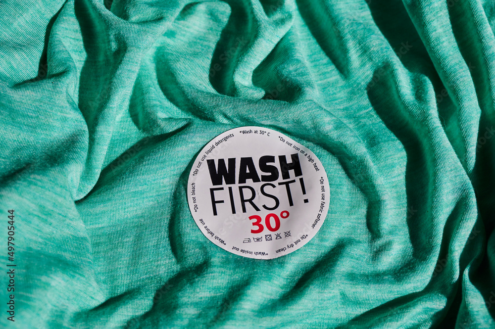 Sticker on a Tshirt with washing instructions and the text "Wash first