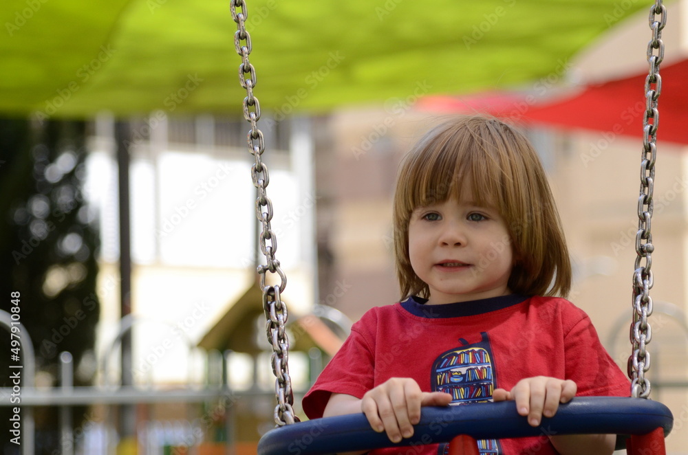 Little cute boy rides on a swing in the playground. The child laughs. close-up portrait Little cute boy rides on a swing in the playground. The child laughs. close-up portrait