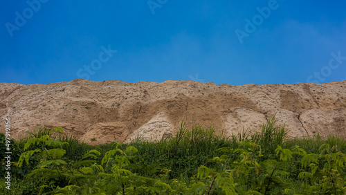 Isolate a landscape of large, mountain-like mounds of sandy soil.