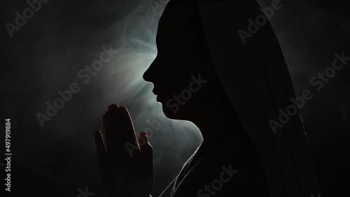 Nun praying in a dark place photo