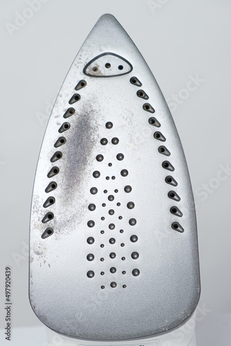 Damaged sole of the iron, brown stains and traces of burning with smoke and steam. Improper behavior during ironing clothes photo