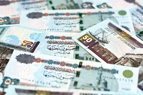 A pile of Egyptian money banknotes of 50 LE fifty pounds features Abu Hurayba Mosque on obverse side and n image of temple of Edfu, winged scarab and a pharaonic boat on the reverse, selective focus photo