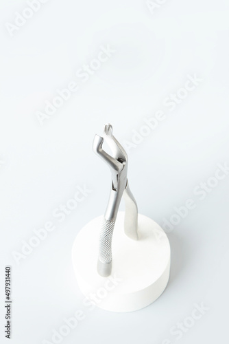 Dental forceps on a light background.Dental instruments.Modern dentistry.Light podium.Vertical photo.Flat lay.Top view.Copy space.
