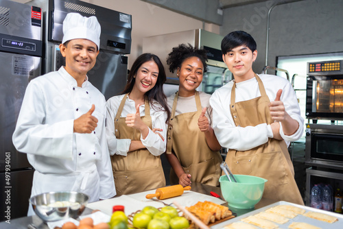 Cooking course , senior Asian male chef in cook uniform teaches young asian and african american people cooking class students to prepare, mix ingredients for pastry foods, in restaurant stainless 