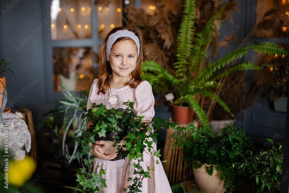 Cute girl holding potted plants in a greenhouse. Little farmer caring for flowers. Country life. The child is engaged in botany love for nature. botanist. Flower shop florist