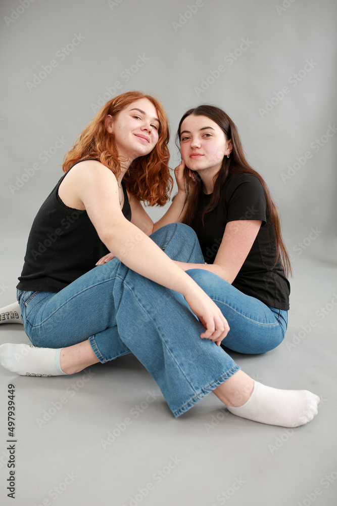 two beautiful girls on a gray background. girlfriends hugging. red hair color. studio photo shoot. female friendship. stop the war two beautiful girls on a gray background. girlfriends hugging. red hair color. studio photo shoot. female friendship. stop the war