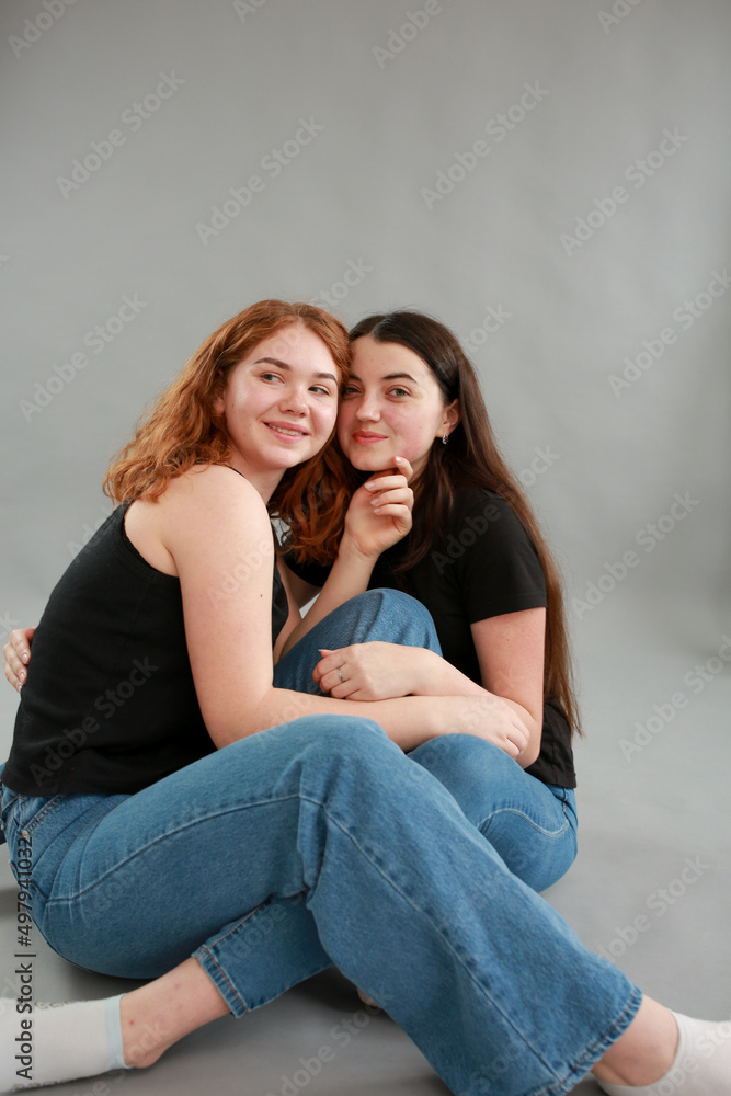 two beautiful girls on a gray background. girlfriends hugging. red hair color. studio photo shoot. female friendship. stop the war two beautiful girls on a gray background. girlfriends hugging. red hair color. studio photo shoot. female friendship. stop the war