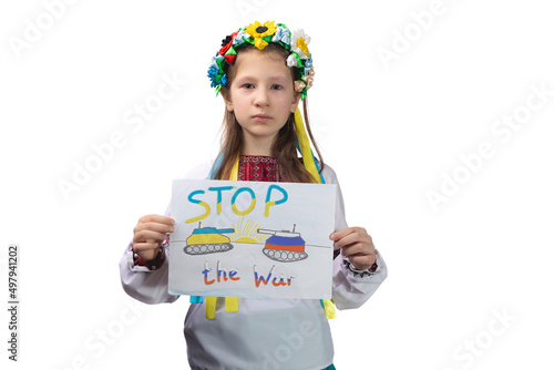 A little Ukrainian girl with tearful eyes holds a drawing with the inscription "Stop the war" in her hands. A child in Ukrainian national clothes.