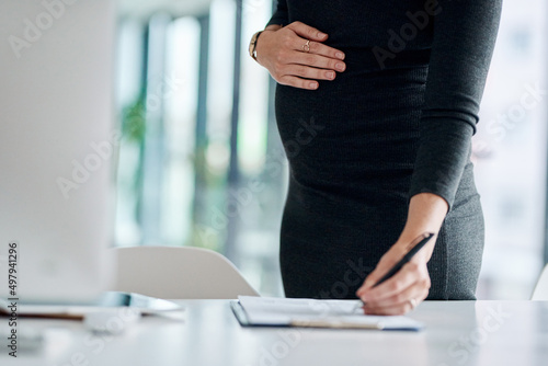 Theres lots to do before she leaves. Closeup shot of a pregnant businesswoman writing notes in an office.