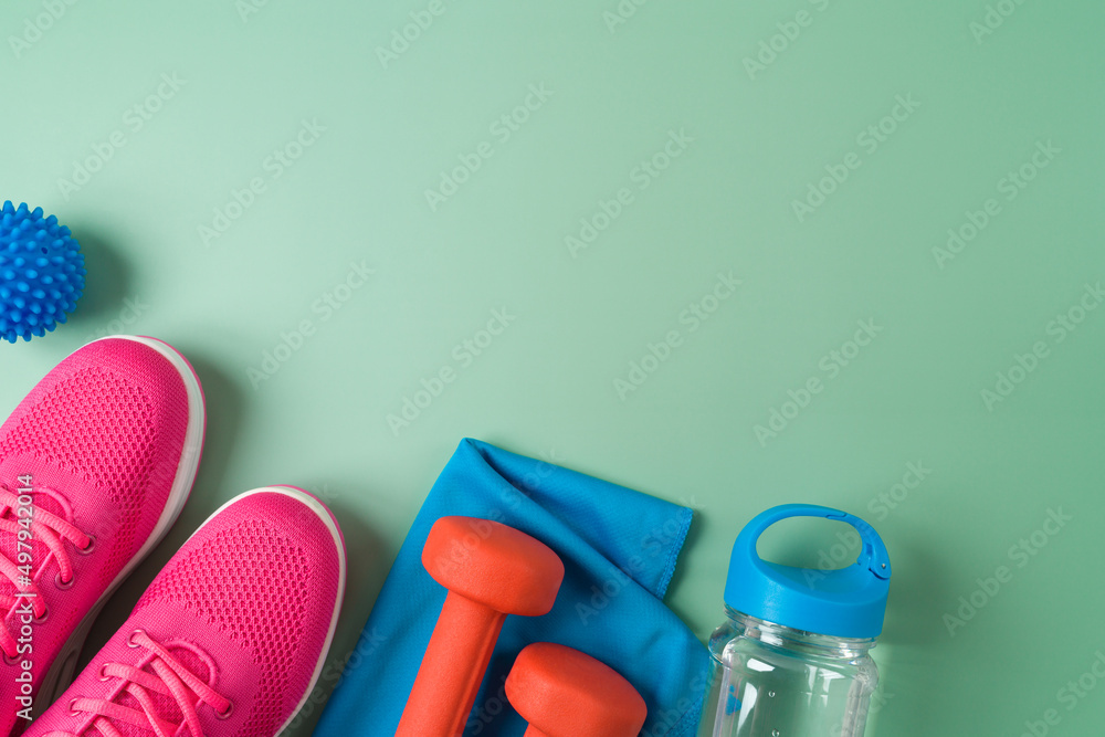 Fitness background with dumbbells, bottle of water, sport shoes and towel. Top view with copy space