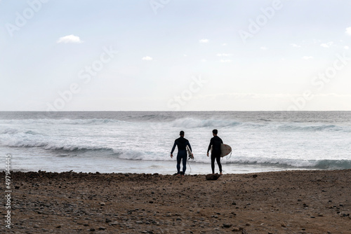 two surfers go to the ocean on the island of Tenerife photo