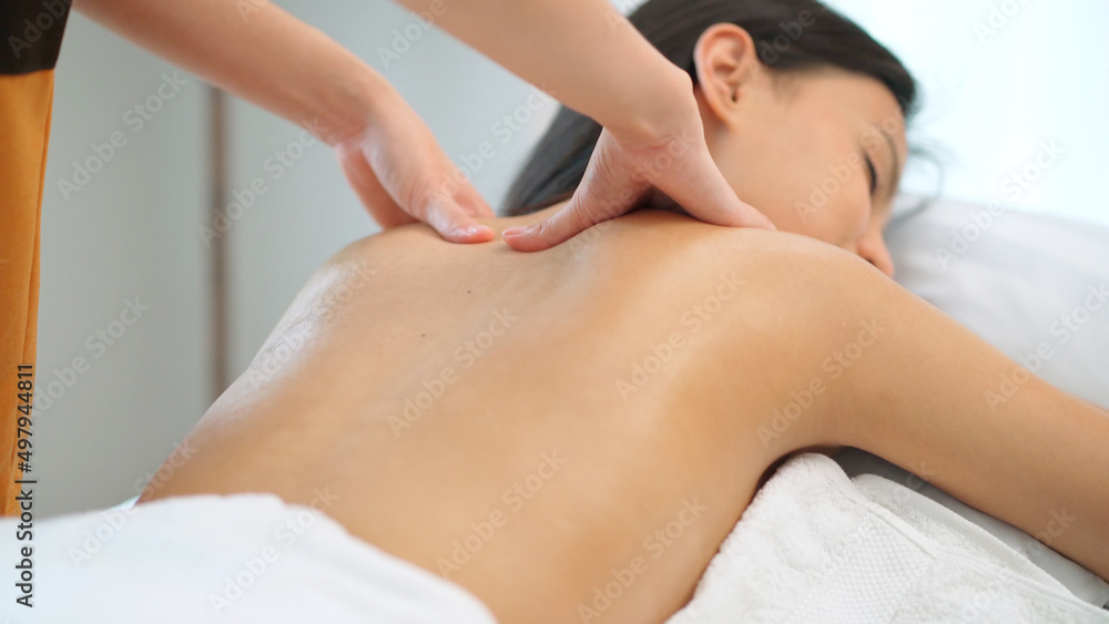 Close up masseur hands doing back massage with oil in the beauty spa. Woman lying down on the spa bed. Relaxing or revitalizing of muscle after work. Enjoying full body care. Healthy and spa concept Close up masseur hands doing back massage with oil in the beauty spa. Woman lying down on the spa bed. Relaxing or revitalizing of muscle after work. Enjoying full body care. Healthy and spa concept