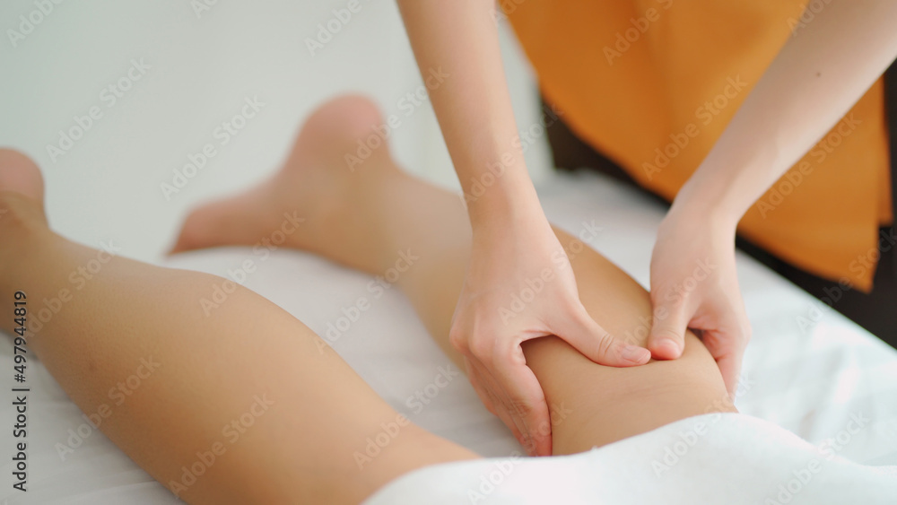 Close up masseur hands doing leg massage with oil in the beauty spa. Woman lying down on the spa bed. Relaxing or revitalizing of muscle after work. Enjoying full body care. Healthy and spa concept Close up masseur hands doing leg massage with oil in the beauty spa. Woman lying down on the spa bed. Relaxing or revitalizing of muscle after work. Enjoying full body care. Healthy and spa concept