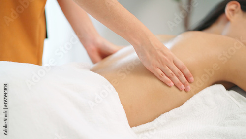 Close up masseur hands doing back massage with oil in the beauty spa. Woman lying down on the spa bed. Relaxing or revitalizing of muscle after work. Enjoying full body care. Healthy and spa concept