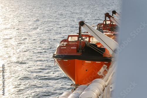 Orange lifeboat on side of north sea ferry boat crossing channel to France or Holland for passengers to escape sinking ship. Emergency life preserve photo