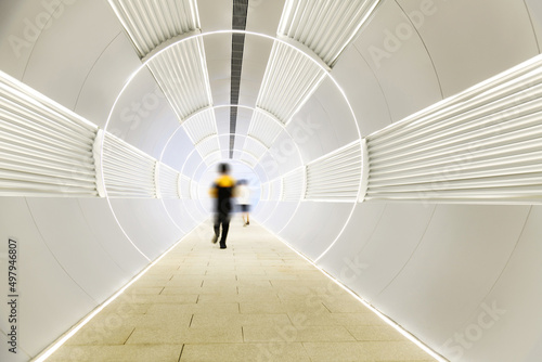 People walking in long futuristic tunnel
