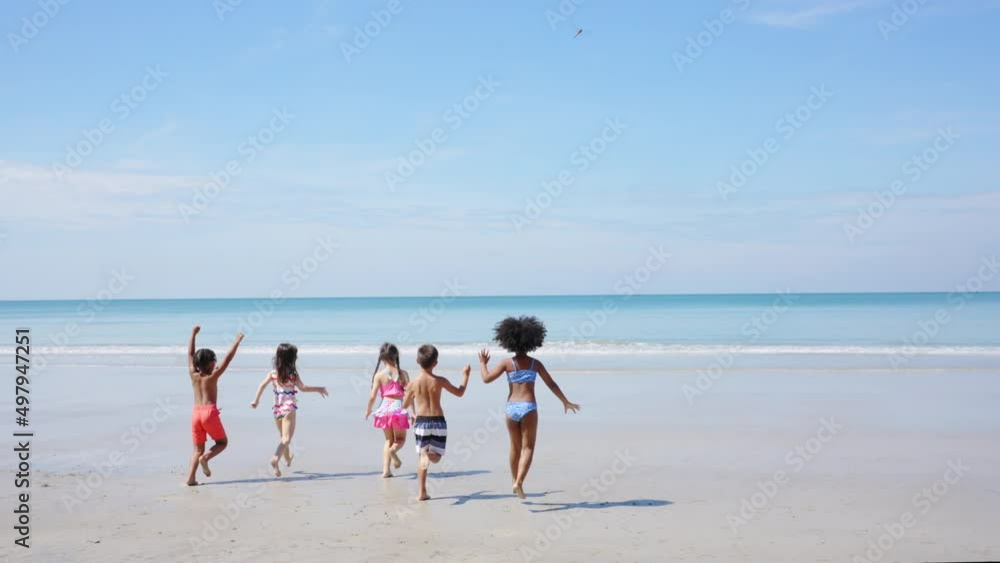 Group of Diversity little child boy and girl friends running and playing in sea water on tropical beach together on summer vacation. Happy children kid enjoy and fun outdoor lifestyle on beach holiday