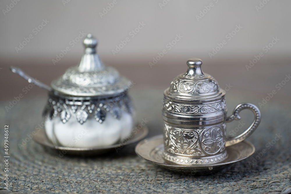 Silver coffee cup and silver sugar jars.close up.