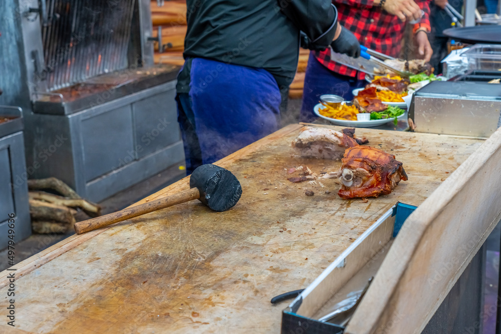 Street grill, fried meat. A man cuts a fried piece of meat into portion. Traditional christmas street food fair in Monaco. Street grill, fried meat. A man cuts a fried piece of meat into portion. Traditional christmas street food fair in Monaco.