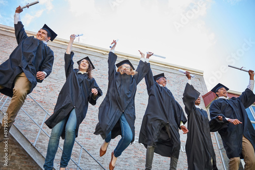 Graduation is a cause for celebration. Low angle shot of a happy group of students jumping in celebration on graduation day.