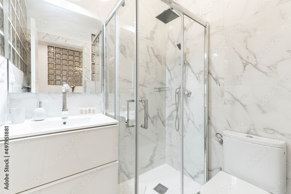 Bathroom with porcelain sink, shower tray, rectangular frameless mirror and walls covered in