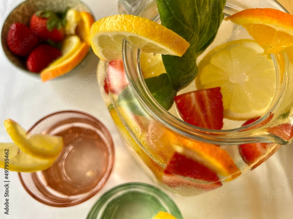 strawberry and lemon infused water in pitcher, glasses and a fruit bowl view from above strawberry and lemon infused water in pitcher, glasses and a fruit bowl view from above