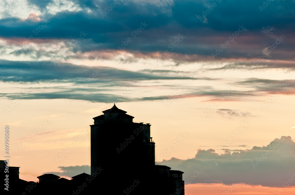 front view, far distance of a silhouetted building with no window lites glowing and the sunsetting behind