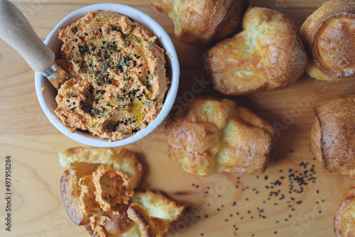 ricotta dip with sun-dried tomatoes and baked paprika in a ceramic white bowl and homemade popovers, which is a puffed, airy, and eggy hollow roll, is fresh from the oven photo