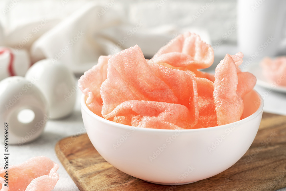 Shrimp chips in a white bowl on a light cooking table. Krupuk udang in a plate closeup Shrimp chips in a white bowl on a light cooking table. Krupuk udang in a plate closeup