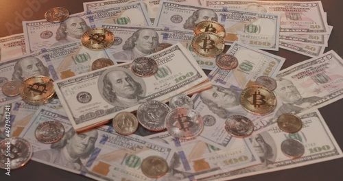 Rotating US Dollar banknotes and gold Bitcoin coins, next to US Dollar coins