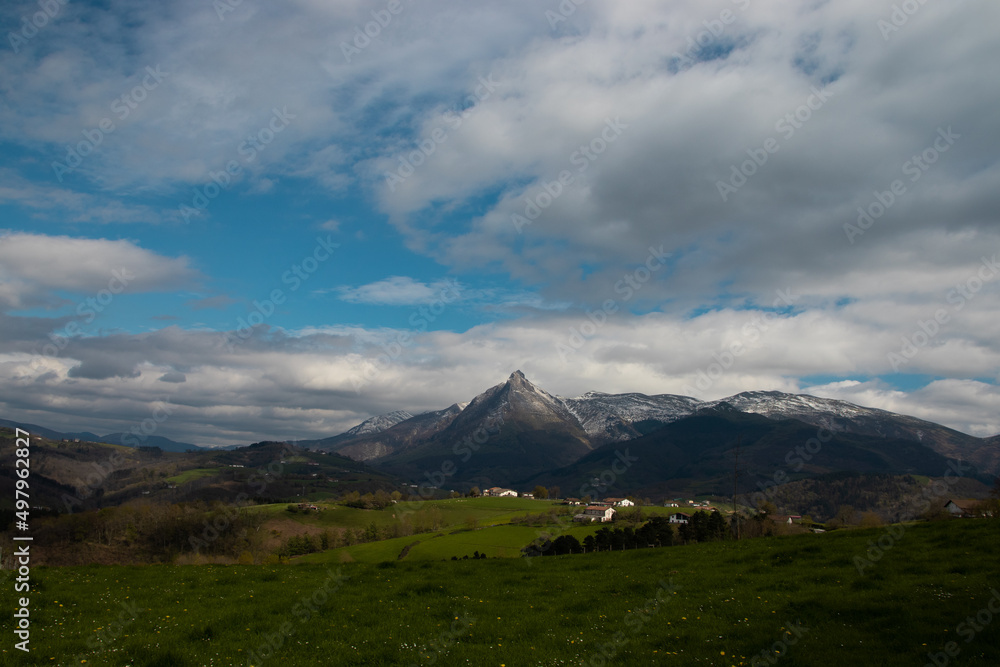 landscape with mountains, clouds and meadow.