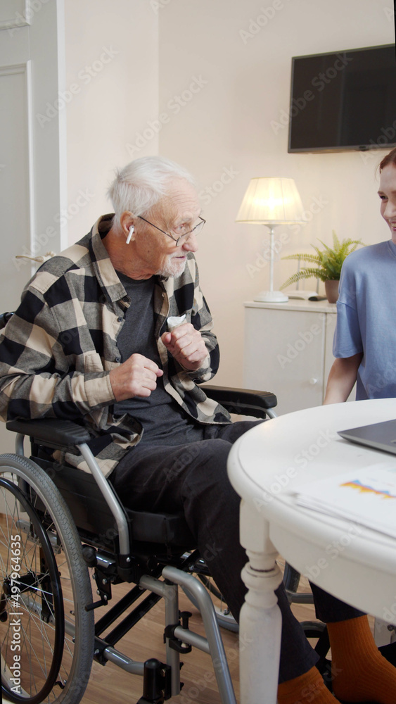 A woman from social care plays an elderly wheelchair user his favorite music. He rejoices and dances A woman from social care plays an elderly wheelchair user his favorite music. He rejoices and dances