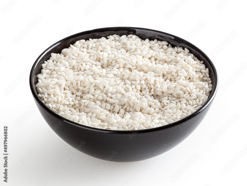 Uncooked arborio rice in black ceramic bowl isolated on white background with clipping path Uncooked arborio rice in black ceramic bowl isolated on white background with clipping path